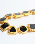 Collar dorado con figuras geométricas negras